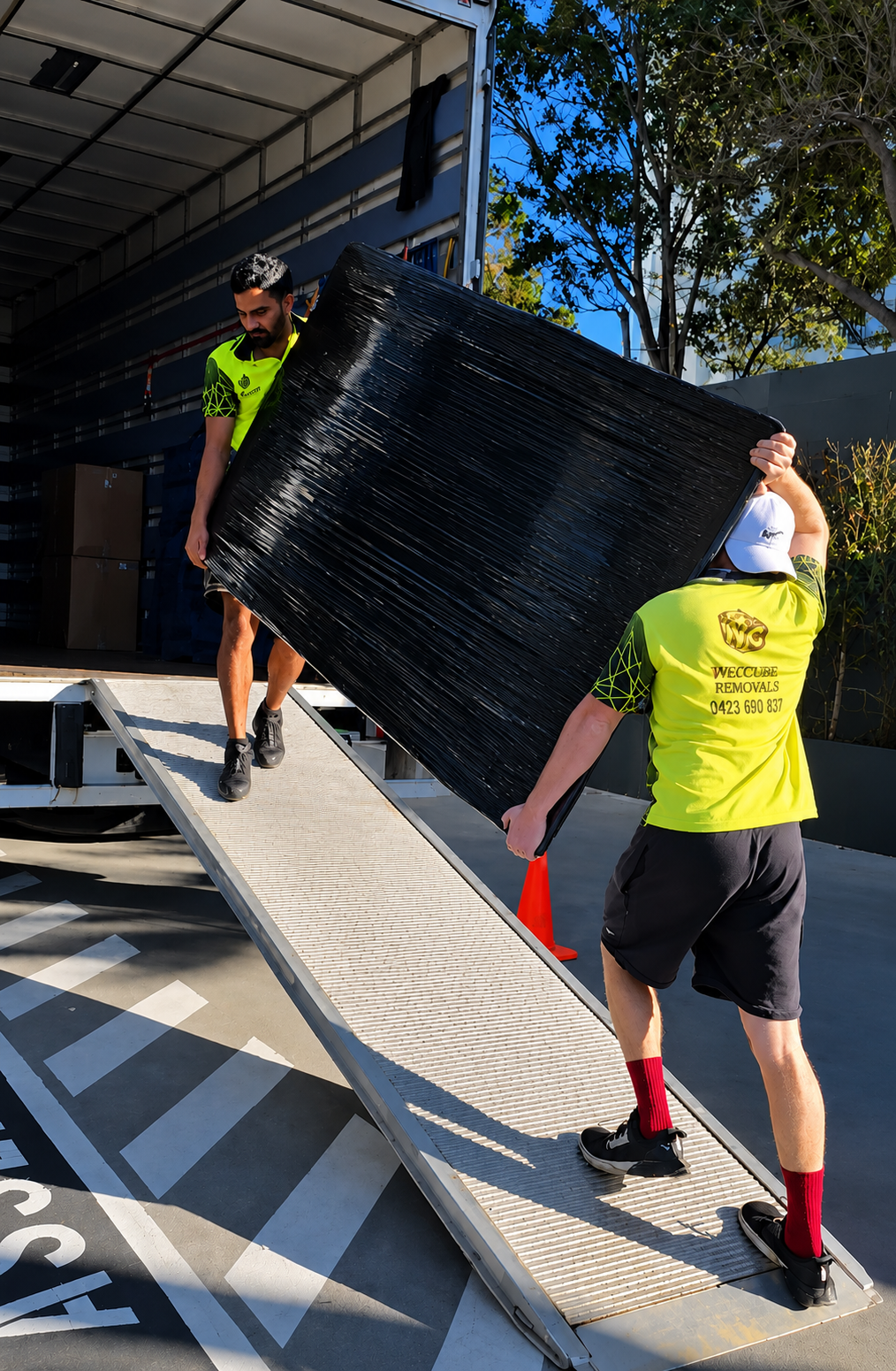 Wecube Removals uniformed team carefully loading wrapped furniture into a truck outside a Queensland home